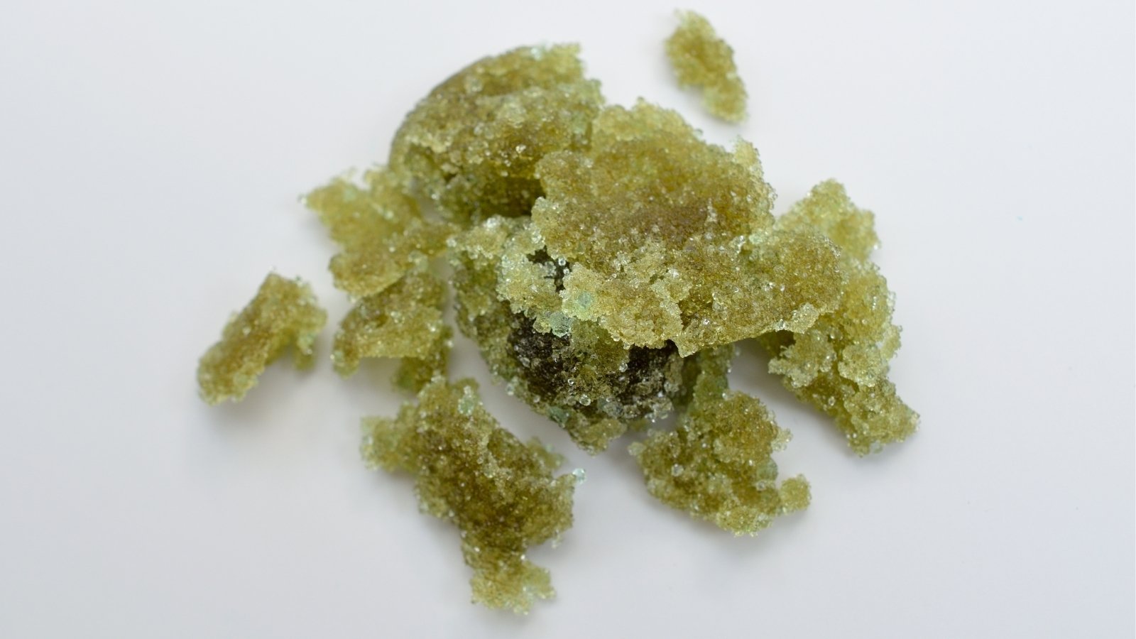 Iron Sulfate sits in stark contrast against a pristine white surface, its green coloration drawing the eye. Tiny crystalline structures sparkle under the light, hinting at the compound's molecular complexity. Its presence suggests a role in horticulture or industry, awaiting its purpose to be fulfilled.